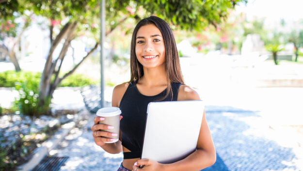 Foto de una estudiante con una laptop y un vaso de café